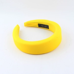 Detail of yellow padded sponge headband featuring a woven HAND MADE label on inner lining