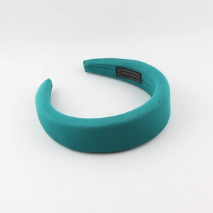 Close-up of teal silk padded headband with handmade label on inner side