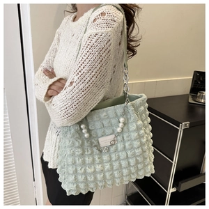 Détail du sac cabas vert clair à texture bulles avec chaîne perle et étiquette cuir