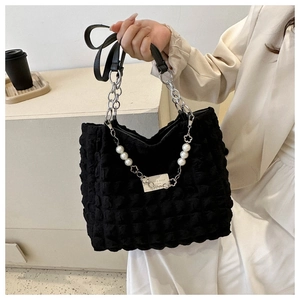 Detail of black bubble texture tote bag with pearl and floral metal chain accessory