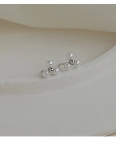Macro shot of elegant clover-shaped stud earrings featuring three white pearls and silver beads