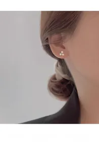 Close-up of elegant triple pearl clover stud earrings worn by a model in black suit