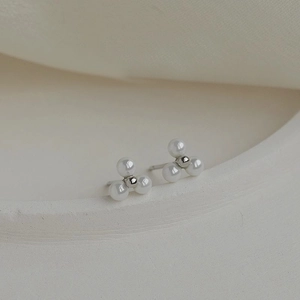 Elegant minimalist earrings featuring three pearls with a silver bead on a white tray