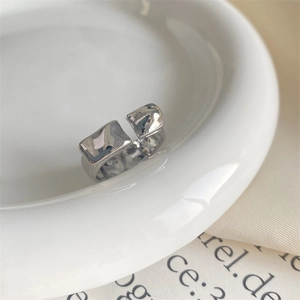 Detailed view of silver open ring featuring irregular lava texture on white ceramic plate