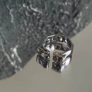 Adjustable silver ring with irregular lava texture design on a gray stone surface