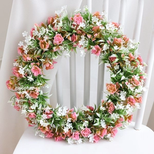 Ghirlanda di fiori di ciliegio artificiali con rose rosa e foglie su una sedia bianca