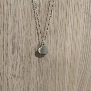 Detail of silver heart pendant necklace featuring a polished finish on a wooden background