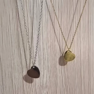 Close-up of minimalist heart pendant necklaces in polished gold and silver finishes