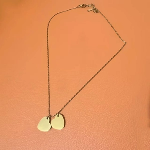 Detail of a minimalist gold heart pendant necklace on an orange textured background