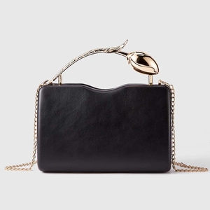 Detail of elegant black PU clutch with a realistic gold rose-shaped metal handle and chain
