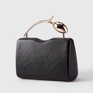 Detail of elegant black evening clutch featuring a gold rose flower metal handle
