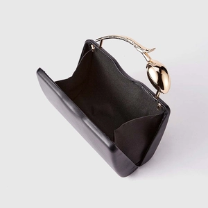 Detail of black evening clutch bag with unique gold tulip-shaped metal handle and inner lining