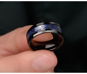 Detailed view of black titanium steel ring with blue carbon fiber and silver Celtic dragon pattern
