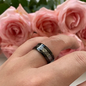 Close-up of polished black titanium steel ring with silver Celtic dragon pattern inlay