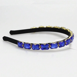 Detail of dark blue rhinestone headband with gold claw settings and black fabric base