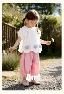 Detail of girls cotton top with purple checkered hearts and pink wide-leg trousers