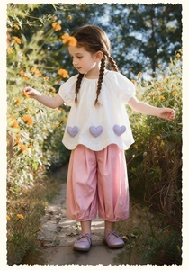 Close-up of white t-shirt with purple gingham heart patches and pink cotton trousers
