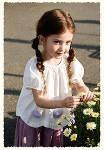 Girl in white puff sleeve top with purple heart pockets and matching loose trousers