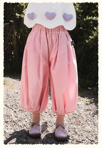 Detail of pink wide-leg pants with elastic waist and white top featuring purple heart patches