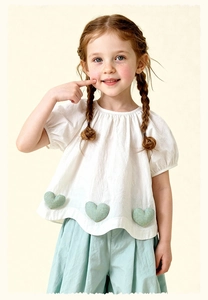 Detail view of white puff sleeve shirt with cute gingham heart patches and blue pants