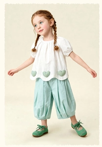 Detail of girls' puff sleeve top with heart patches and mint green harem pants
