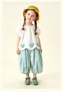Detail of girls' summer outfit with heart patches, wavy hem, and blue wide-leg pants