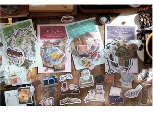 Detalle de pegatinas vintage de café con cámaras y vinilos sobre escritorio de madera