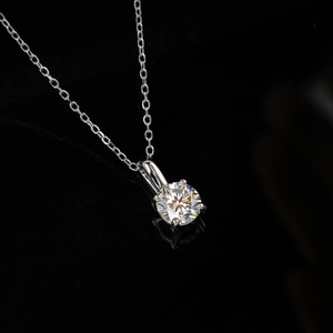 Detailed close-up of a brilliant round diamond pendant in a classic four-prong silver setting