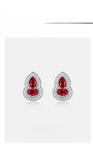 Macro shot of silver Wulu earrings set with red rubies and sparkling white diamonds