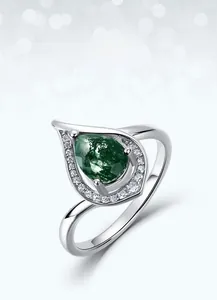 Macro shot of silver ring with pear-cut green moss agate and halo of small diamonds