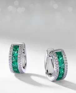 Macro shot of U-shaped silver earrings featuring lab emerald and white zircon pave setting