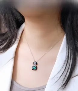 Detail of emerald cut green gemstone pendant necklace on a model wearing a white blazer