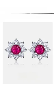Macro detail of S925 silver flower stud earrings featuring red ruby and clear zircons