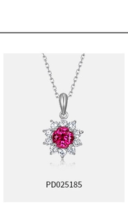 Macro detail of sunburst floral pendant featuring center ruby stone and zircon petals