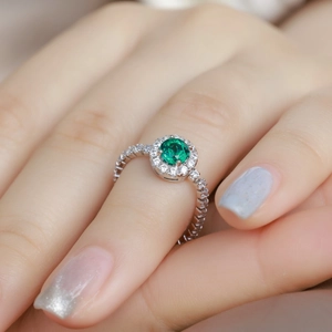 S925 sterling silver halo ring with round green emerald and pave set stones on hand