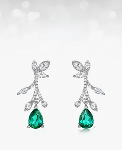 Macro shot of silver vine earrings with lab-grown emerald drops and white cubic zirconia