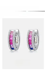 Detail of silver huggie earrings with gradient colored gems and sparkling white zircons