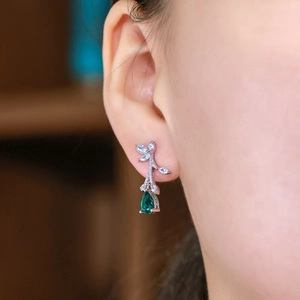 Elegant S925 silver leaf earrings with lab emerald drops worn by a model in soft light