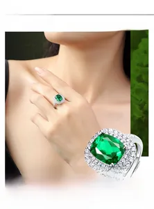 Macro shot of silver ring featuring halo-set emerald cut green gemstone with micro-pave