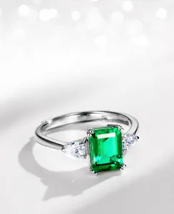 Gros plan d'une bague émeraude avec pierres latérales en poire sur anneau en argent
