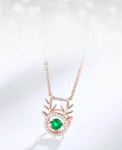 Macro detail of rose gold deer antler pendant featuring emerald gemstone and small zircons