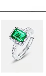 Macro view of emerald-cut green gemstone ring with halo diamond setting in silver
