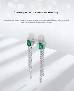Macro view of S925 silver bow stud earring featuring square emerald and long diamond tassels