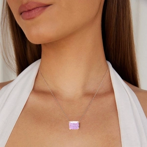Elegant gold necklace with a large radiant-cut pink gemstone pendant worn by model
