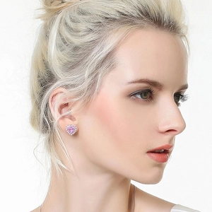 Gros plan d'un clou d'oreille en forme de cœur rose porté avec des accents brillants
