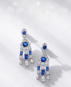 Detailed view of long tassel earrings with blue square stones and silver plating