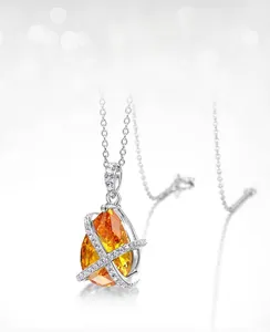 Macro detail of pear-cut orange carbon diamond pendant with cross prong setting on silver chain
