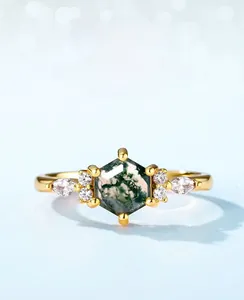 Macro shot of hexagonal green moss agate ring with marquise side stones on a gold band