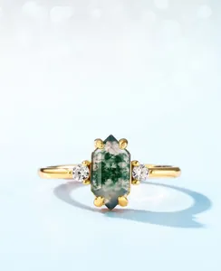 Macro shot of hexagon-cut green moss agate ring with side stones in gold plating
