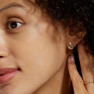 Close-up of moss agate gold stud earrings with cubic zirconia on a model's ear